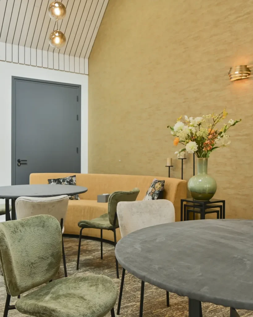 Koffiekamer van rouwcentrum 't Waerdsche Hof met ronde tafels en bloemen