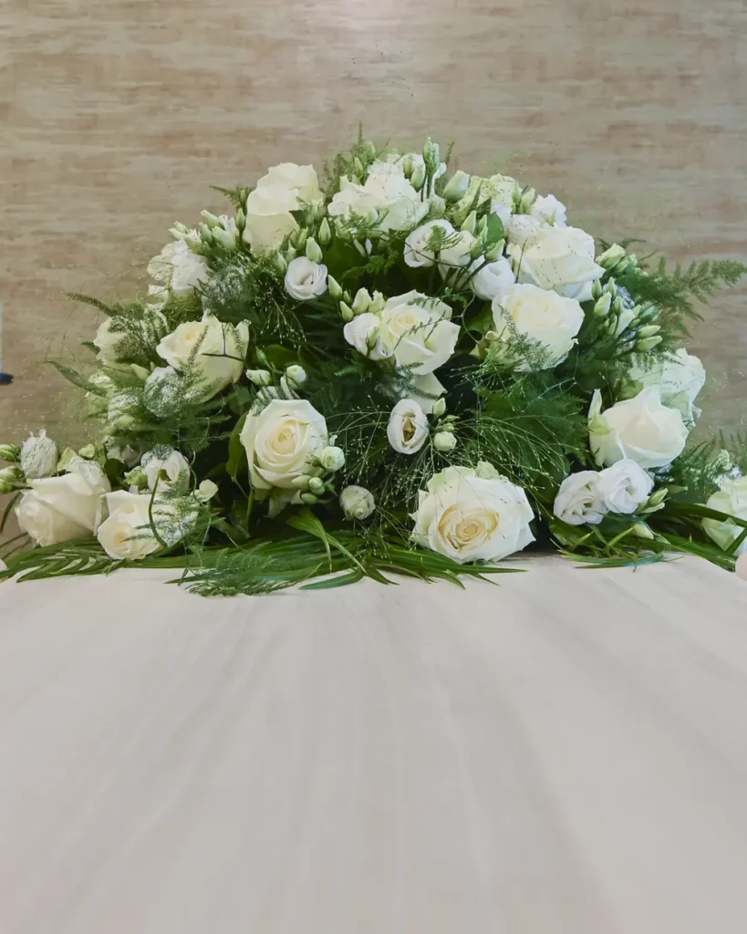 Bloemstuk van witte rozen op een uitvaartkist