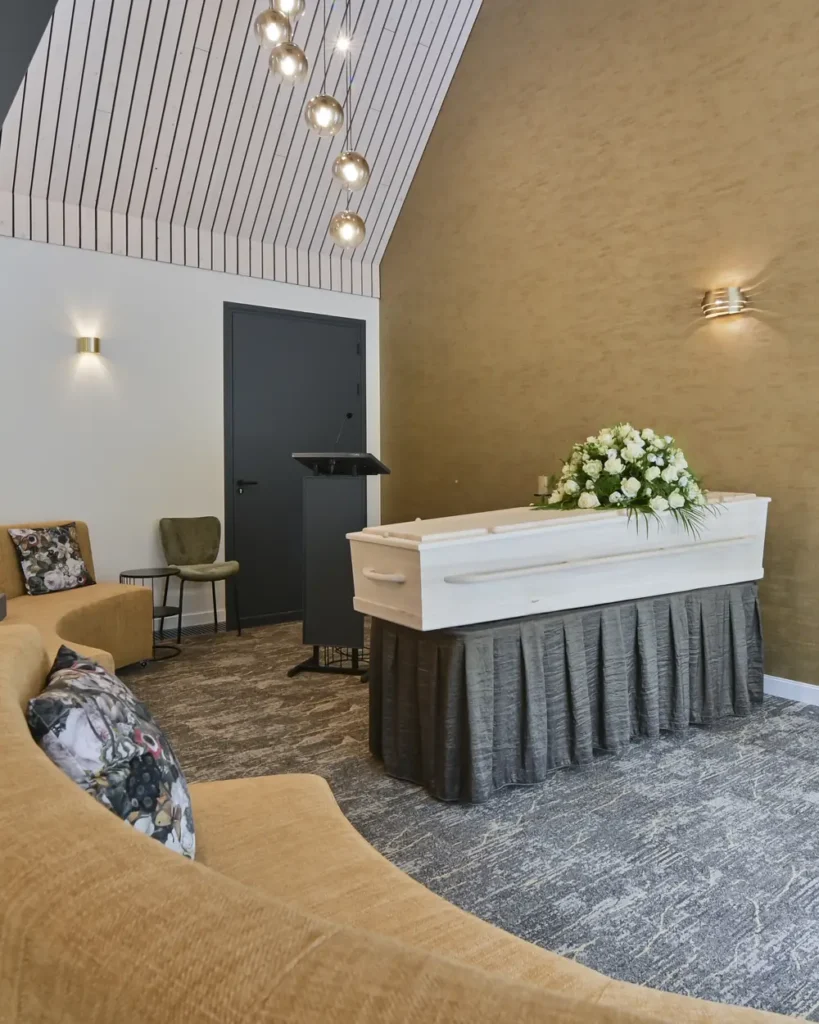 Aula van rouwcentrum 't Waerdsche Hof met een witte kist en een spreekgestoelte
