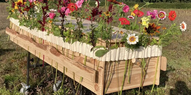 Houten uitvaartkist met een band van verse veldbloemen